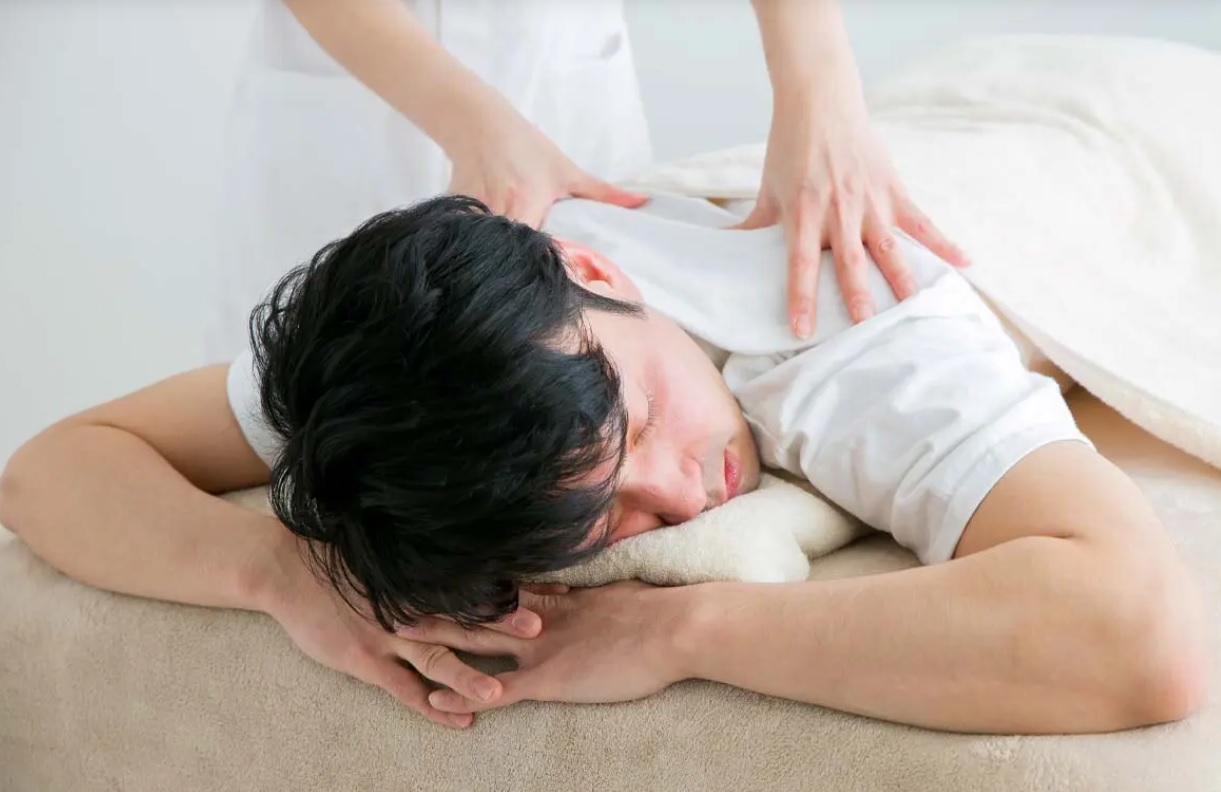 Praticien effectuant un massage Tuina traditionnel chinois sur un patient habillé